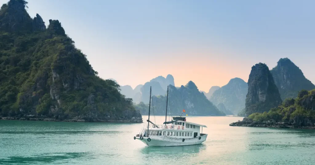 Barcos tradicionais navegando na Baía de Ha Long, Vietnã, com ilhas calcárias ao fundo. Uma rica ideia de viagem no verão para imersão cultural e paisagens exóticas.