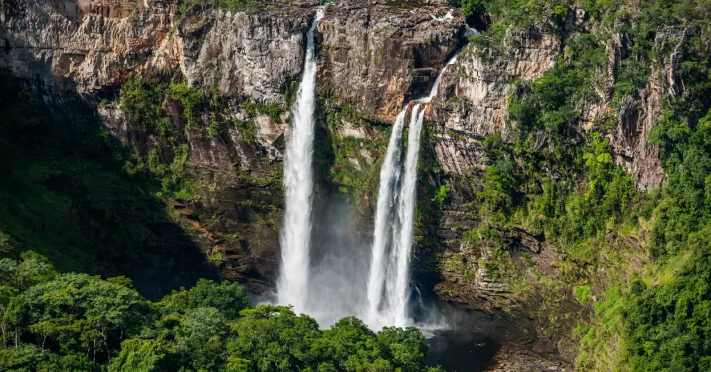 Cachoeira imponente na Chapada dos Veadeiros, Goiás, com águas volumosas em meio à vegetação verde. Uma ideia de viagem no verão para amantes do ecoturismo e trilhas.