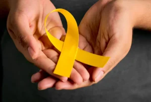 Pessoa meditando com laço amarelo. Mídia quebra o tabu e promove o cuidado da saúde mental durante Setembro Amarelo.